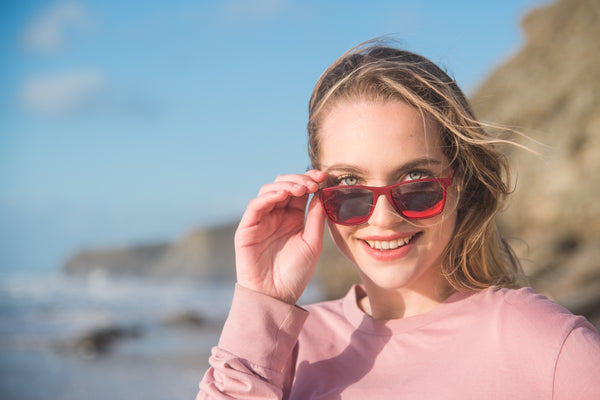 Model wearing red polarised sunglasses on Newquay Beach during Boardmasters